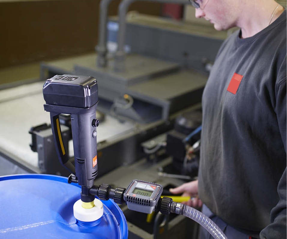 En person som pumpar vätska från ett plastfat med en batteridriven fatpump.