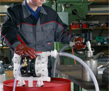 En person som pumpar vätska från en fat till en kanna med hjälp av en tryckluftsdriven pump.
