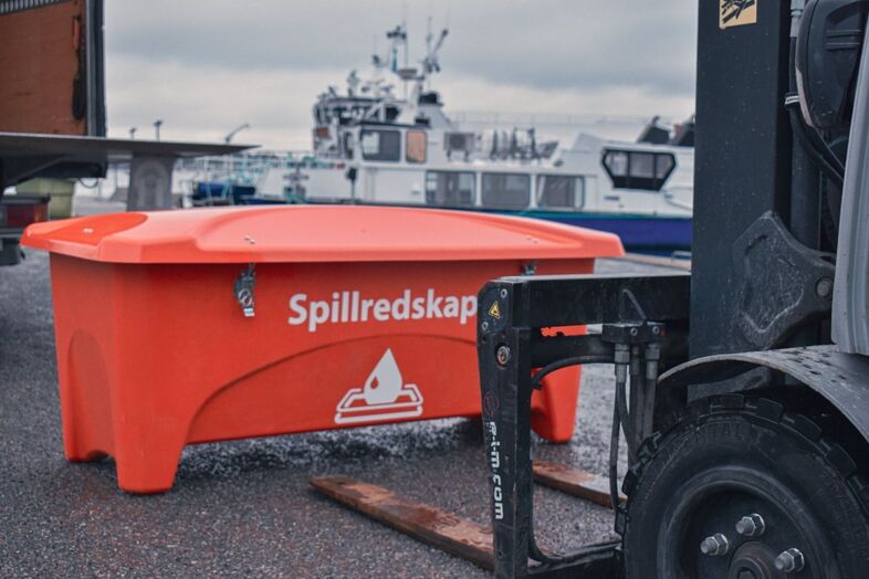 En orange redskapsbox med texten spillredskap som står framför en truck.