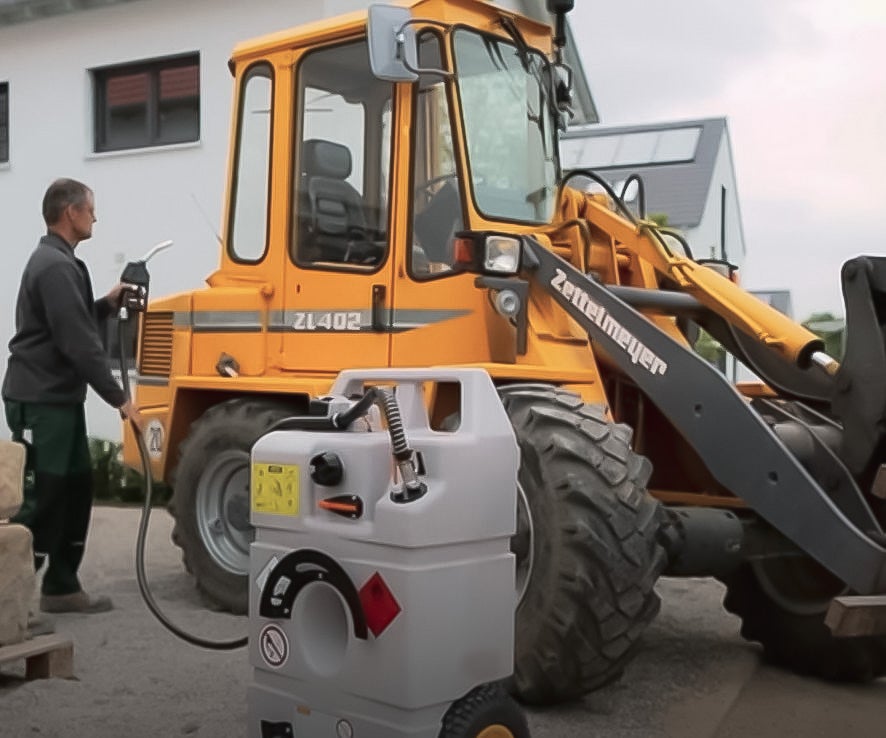 En person vid en traktor som tankar den med hjälp av en mobil transporttank med diesel.
