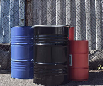 En grupp med plåtfat, 200 liters och 60 liters i olika färger - svart, röd, blå.